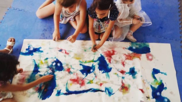 Niños pintando juntos sobre un papel grande extendido en el suelo
