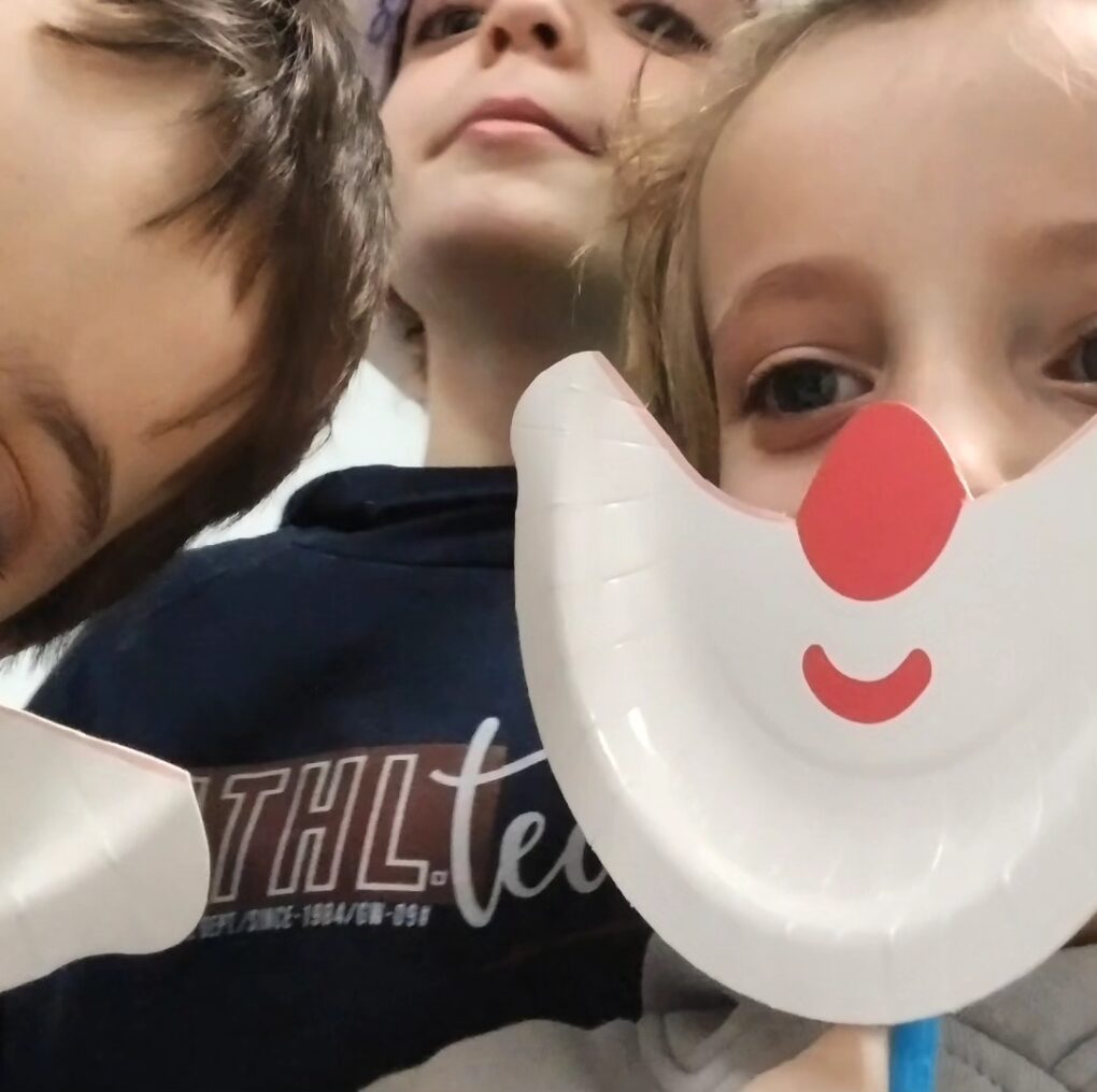 Niños con máscaras de papel con forma de cara hechas en el taller