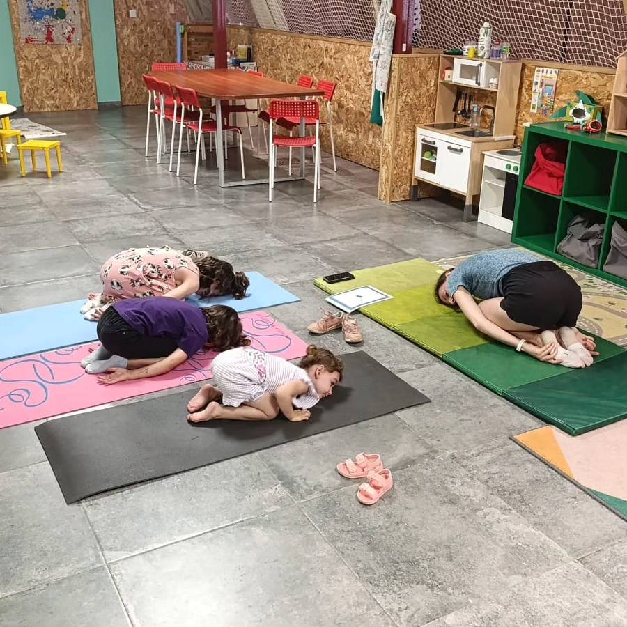 Niños haciendo estiramientos sobre esterillas en el suelo del aula