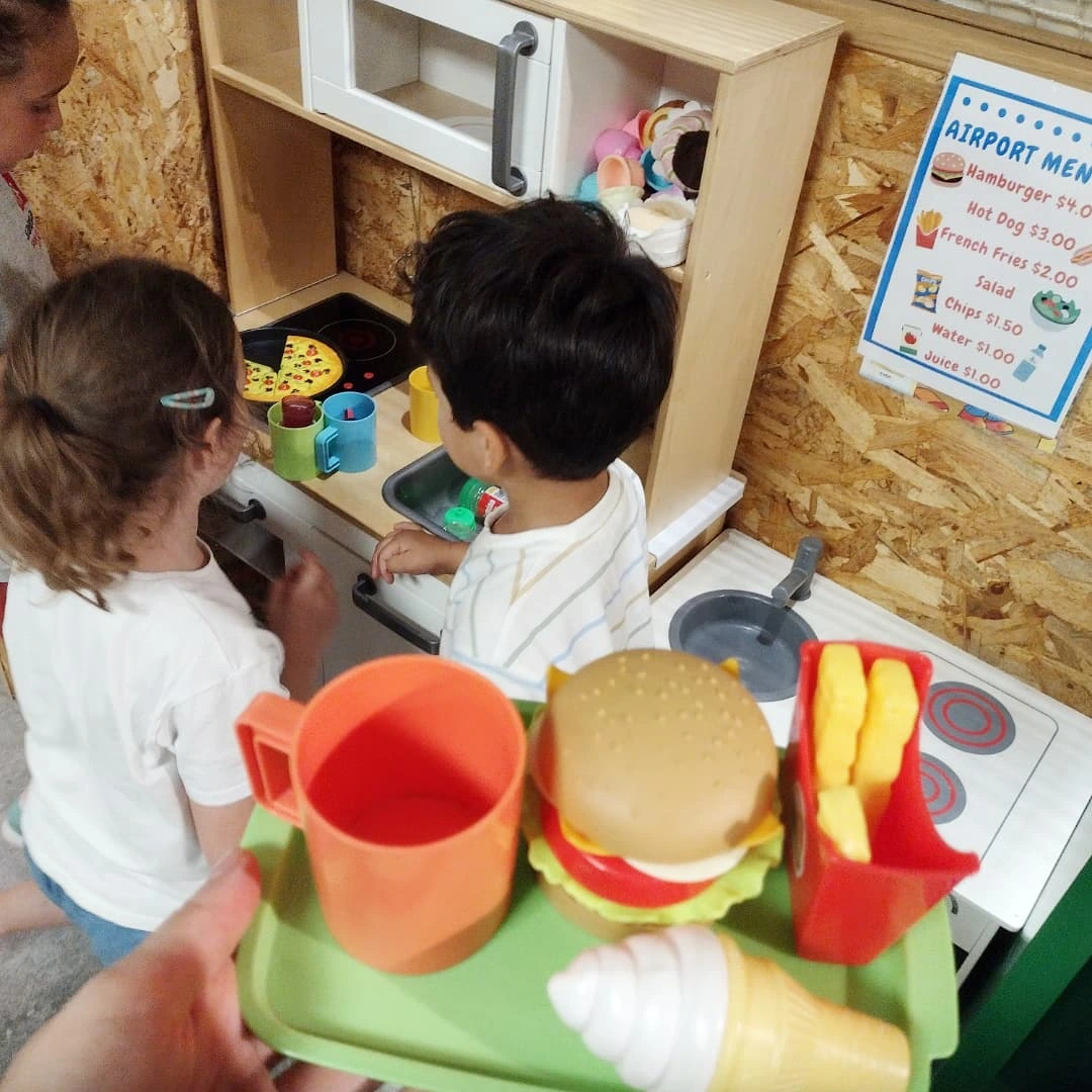 Niños jugando a la cocinita con comida de juguete para practicar vocabulario en inglés