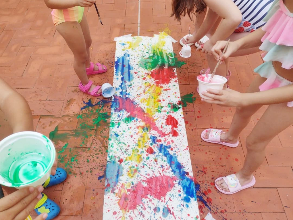 Niños pintando con témperas de colores sobre papel en el suelo