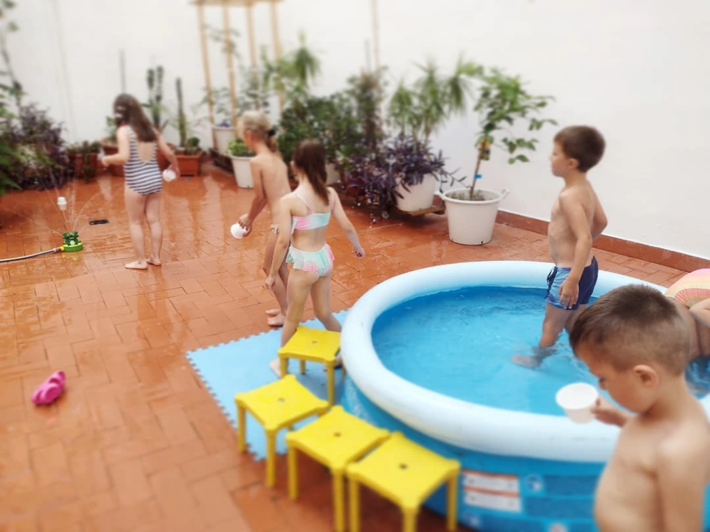 Niños jugando en el patio junto a una piscina hinchable en verano